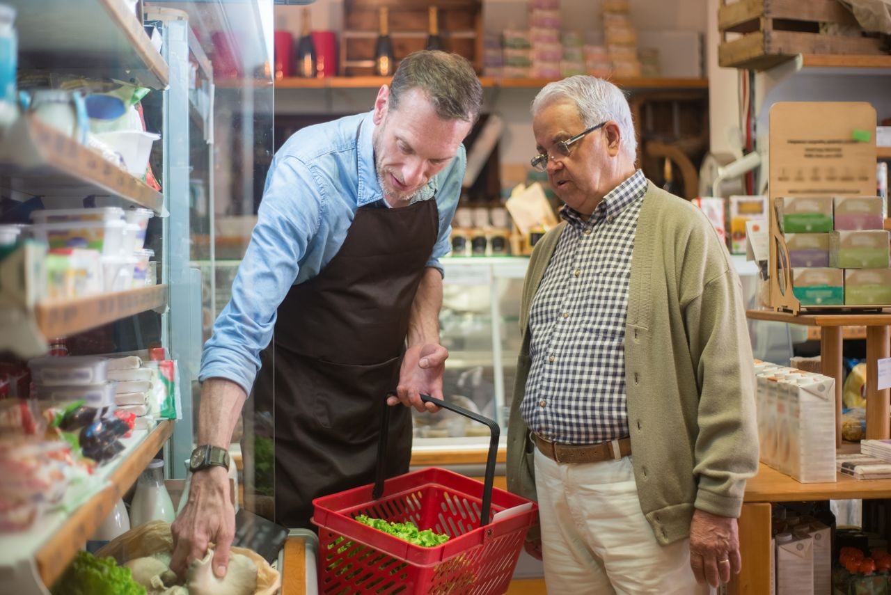Free A salesman helps an elderly man with shopping in a local grocery store. Stock Photo